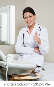 Portrait of an Indian female radiologist gesturing thumbs up while sitting by ultrasound machine