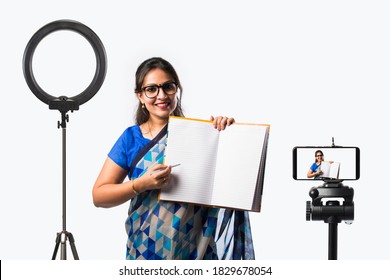 Portrait Of Indian Lady Teacher In Saree Stands Against Green, White Or Blackboard , Conducting Online Class Using Camera, Internet And Lights