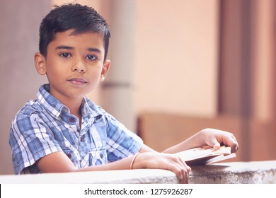 Portrait Of Indian Little Boy Posing To Camera With School Text Book