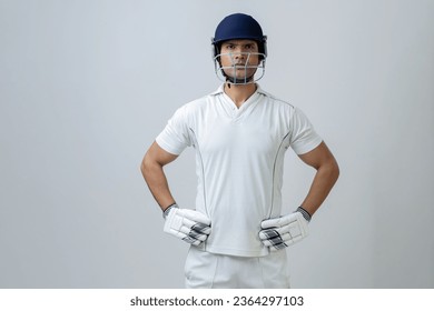 portrait of indian Man in cricket dress with helmet and gloves. Cricketer portrait in studio light looking towards the camera - Powered by Shutterstock