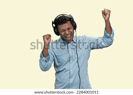 Portrait of Indian man listen to music in headphones and singing. Isolated on white background.