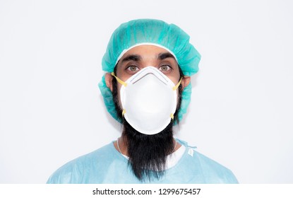 Portrait of Indian man with long mustache in hat and mask N 95,Handsome bearded man is black hair and dark brown eyes in white doctor uniform standing against white background and copy space,Sikh man, - Powered by Shutterstock