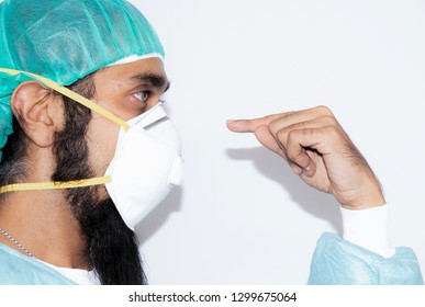 Portrait of Indian man with mustache wearing hat and mask N 95,Handsome bearded man is black hair and dark brown eyes wear white doctor uniform and focus finger to mask N95 and copy space,Sikh man, - Powered by Shutterstock