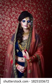 Portrait Of An Indian Muslim Bride Wearing Red Sari With Heavy Jewelry In A Banquet Hall. Traditional Muslim Bride In Wedding.