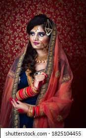 Portrait Of An Indian Muslim Bride Wearing Red Sari With Heavy Jewelry In A Banquet Hall. Traditional Muslim Bride In Wedding.