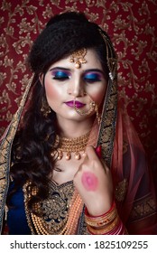 Portrait Of An Indian Muslim Bride Wearing Red Sari With Heavy Jewelry In A Banquet Hall. Traditional Muslim Bride In Wedding.