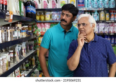 Portrait Of Indian Old Father And Mid Aged Son Purchasing In A Grocery Store. Confused Father And Son Buying Grocery For Home In A Supermarket. Both Are Thinking And Totally Perplexed. 