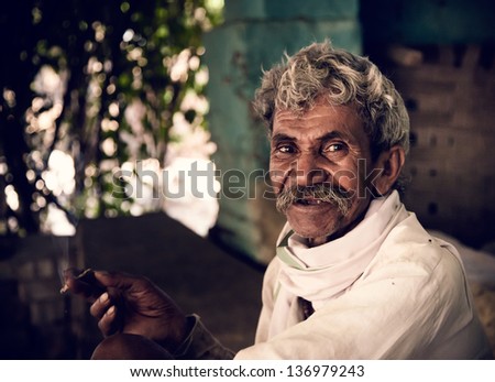 Portrait of an Indian old villager man smiling while smoking bidi.