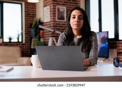 Portrait Of Indian Person Working From Home On Laptop At Desk, Browsing Internet And Sending Email With Paperwork Report. Using Computer To Study Online At Class Webinar, Freelancer Work.