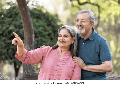 Portrait of Indian senior couple embracing while standing in park. - Powered by Shutterstock