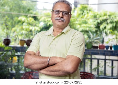 Portrait indian senior man wearing eye glasses standing cross arm indoors, Retired asian old male. - Powered by Shutterstock