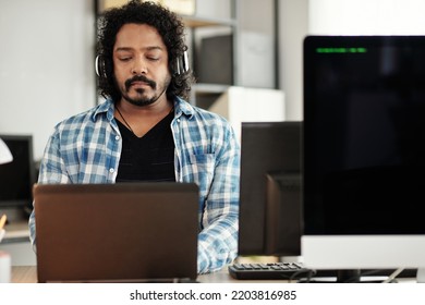 Portrait Of Indian Software Developer Listening To Music In Headphones And Coding On Laptop