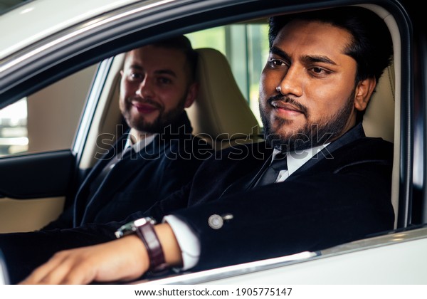 portrait of indian taxi driver driving hiss boss at\
work business male inside limousine.tourist in asia business\
conference in india