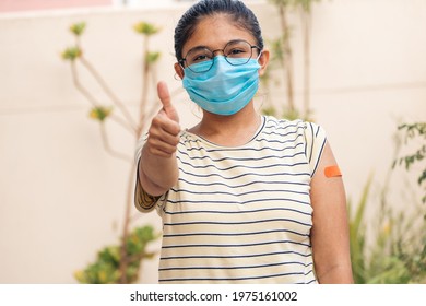 Portrait Of An Indian Teen Girl Giving Thumbs Up After Getting Vaccinated And Showing Bandage On His Arm