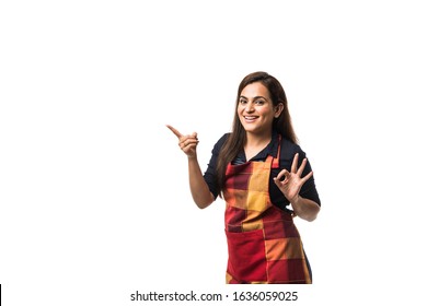 Portrait Of Indian Woman Chef Or Cook In Apron, Presenting, Pointing, With Ok Sign, Thumbs Up Or Hands Folded. Standing Isolated Over White Background