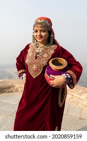 Portrait Of An Indian Woman Wearing Ethnic Kashmiri Dress And Carrying A Mud Pot As She Poses For A Tourist Photo