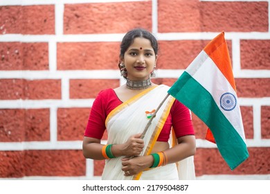 Portrait of indian woman wearing traditional clothes holding Indian flag on national celebration Independence day or  Republic day.  Red brick wall background
