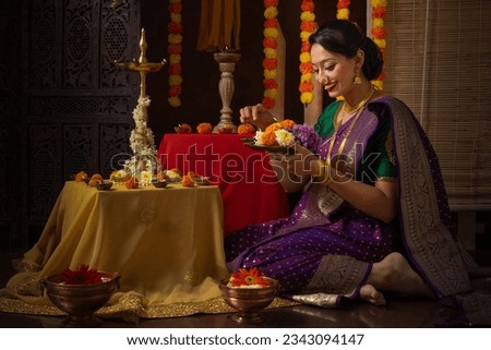 Portrait of Indian young lady performing Hindu rituals of pooja and celebrating the Hindu festival Diwali. Celebration of the Indian festival by young Indian Lady. Diwali festival celebration.