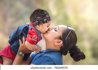 Portrait of Indian/Asian mother Kissing her cute little daughter in the park, Family outdoor lifestyle. - Powered by Shutterstock