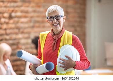 Portrait Of Individual Architect. Senior Female Architect Smiling To Camera In An Office. Portrait Of Female Architect Working On Plans. Portrait Of Smiling Female Architect In Modern Studio