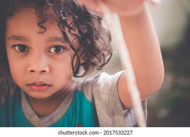 Portrait Of An Indonesian Boy With Curly Hair With A Funny Expression. A Kid Model Is Posing For The Camera.