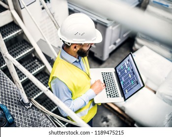 A Portrait Of An Industrial Man Engineer With Laptop In A Factory, Working.