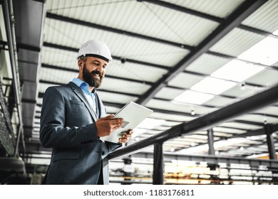 A Portrait Of An Industrial Man Engineer With Tablet In A Factory.