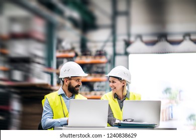 A Portrait Of An Industrial Man And Woman Engineer With Laptop In A Factory, Working.