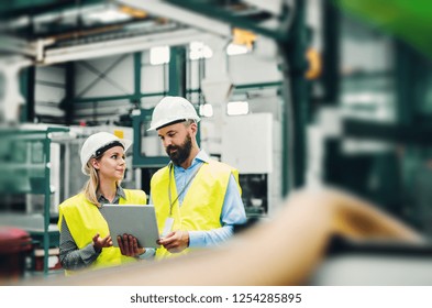 A Portrait Of An Industrial Man And Woman Engineer With Tablet In A Factory.