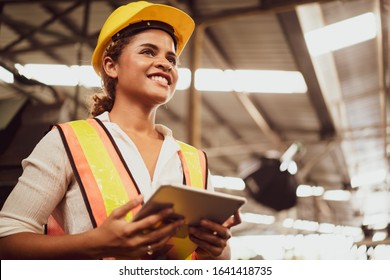 Portrait of an industrial woman worker standing with a big smile feeling proud and confident looking ahead in warm natural light, concept manufacturing industry, engineering worker finding new job. 