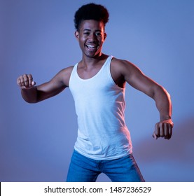 Portrait of inspired cool african american teenager man dancing feeling the music and enjoying life on blue moody disco neon light background. In People, Youth Party night lifestyle. Studio shot. - Powered by Shutterstock