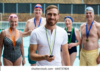 Portrait of instructor with senior men and women at poolside - Powered by Shutterstock