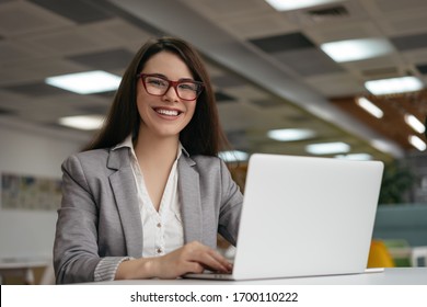 Portrait Of Insurance Agent Using Laptop Computer, Working At Workplace. Successful Business Woman Looking At Camera And Smiling, Sitting In Modern Office