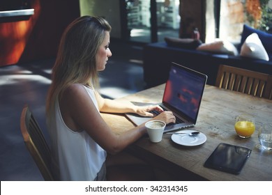 Portrait of intelligent female sitting front laptop computer with copy space screen for your information, young business woman work on net-book during breakfast in coffee modern shop