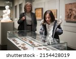 Portrait of interested cheerful preteen girl looking at exposition in historical museum..