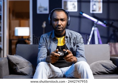 Portrait of irritated gamer upset after losing in online multiplayer videogame played using controller. Man frustrated after seeing game over message while playing on console