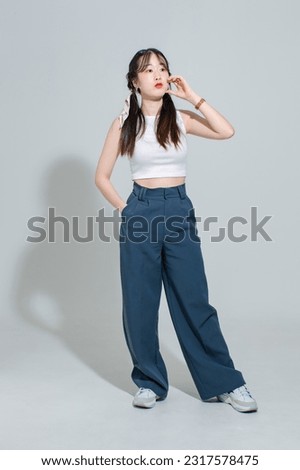 Portrait isolated cutout full body studio shot Asian young pretty female fashion model with pigtails braids hair in fashionable sleeveless crop top standing posing look at camera on white background.