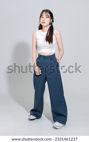 Portrait isolated cutout full body studio shot Asian young pretty female fashion model with pigtails braids hair in fashionable sleeveless crop top standing posing look at camera on white background.