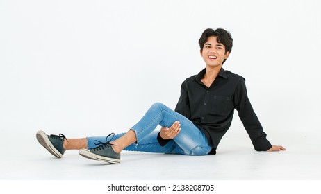 Portrait isolated cutout studio shot of Asian young LGBTQ gay glamour male model in casual black shirt and jeans outfit sitting stretching posing gesturing on floor look at camera on white background. - Powered by Shutterstock