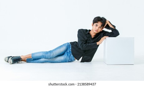 Portrait isolated cutout studio shot of Asian young LGBTQ gay glamour male model in casual black shirt and jeans outfit sitting stretching posing gesturing on floor look at camera on white background. - Powered by Shutterstock