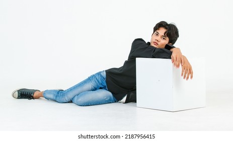 Portrait Isolated Cutout Studio Shot Of Asian Young LGBTQ Gay Glamour Male Model In Casual Black Shirt And Jeans Outfit Sitting Stretching Posing Gesturing On Floor Look At Camera On White Background.