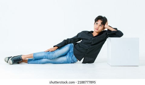 Portrait Isolated Cutout Studio Shot Of Asian Young LGBTQ Gay Glamour Male Model In Casual Black Shirt And Jeans Outfit Sitting Stretching Posing Gesturing On Floor Look At Camera On White Background.