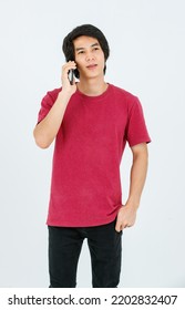 Portrait Isolated Cutout Studio Shot Of Asian Young Handsome Teenager Male Model In Street Style Outfit Standing Holding Smartphone In Hands Smiling Taking Selfie Photo On White Background.