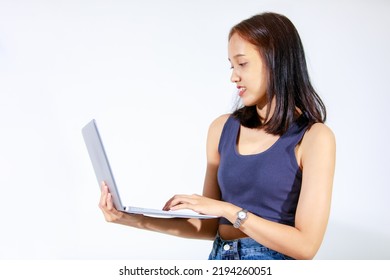 Portrait Isolated Studio Cutout Shot Of Asian Female Model Smiling Look At Camera Holding Pointing Green Blank Screen Laptop Computer Showing Product Promotion Advertisement On White Background.