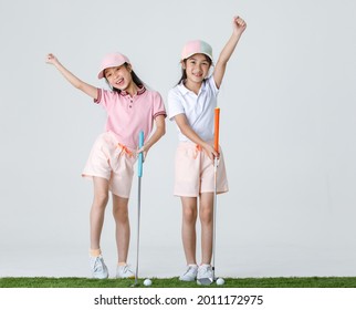 Portrait isolated studio shot of two Asian little professional girl golfers in  athlete fashion clothing stand smile hold fist up overhead when receive victory win in game in front white background. - Powered by Shutterstock