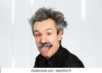 Portrait Of Jocular Aging Man With Grey Long Hair Sticking His Tongue Out In Einstein Manner.