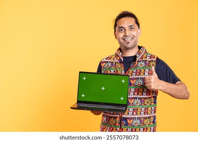 Portrait of jolly tech expert presenting green screen laptop, doing thumbs up gesturing, studio background. Upbeat person doing positive hand gesture while reviewing chroma key notebook - Powered by Shutterstock