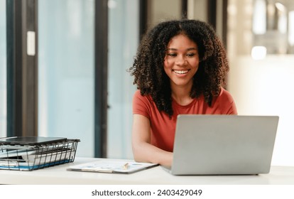 Portrait of joyful African American woman people with an afro hairstyle, working on a laptop at a desk with documents. - Powered by Shutterstock