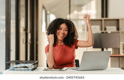 Portrait of joyful African American woman people with an afro hairstyle, working on a laptop at a desk with documents. - Powered by Shutterstock