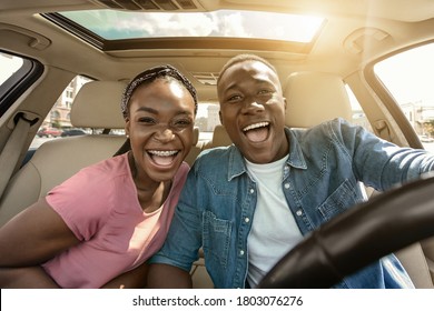 Portrait Of Joyful African Couple In Car, Enjoying Road Trip, Sun Flare